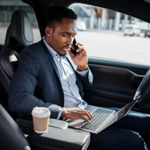 businessman-talking-mobile-typing-laptop-car