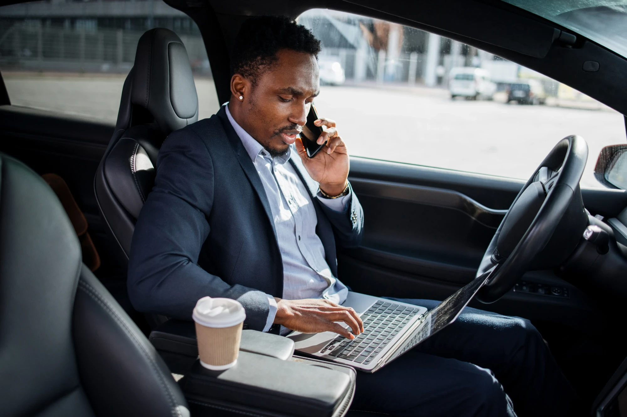 businessman-talking-mobile-typing-laptop-car